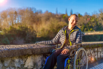 A disabled person in a wheelchair in a park at sunset smiling