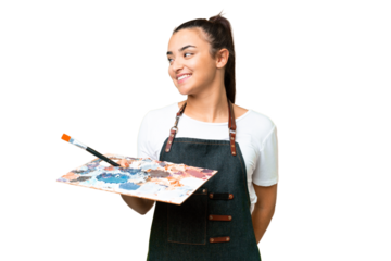 Young artist woman holding a palette over isolated chroma key background looking to the side and smiling