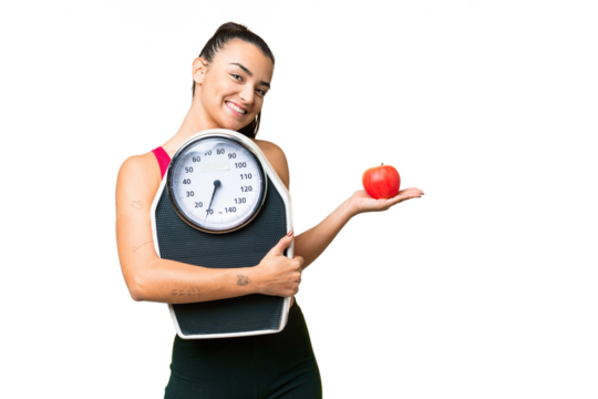 Young beauty woman over isolated chroma key background with weighing machine and with an apple