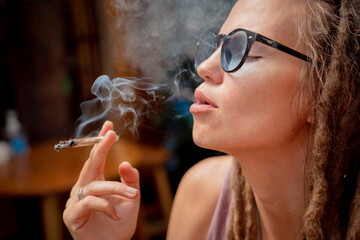 Fototapeta premium Hippie style woman smoking cigarettes with medical marijuana