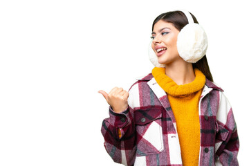 Young Russian woman wearing winter muffs over isolated chroma key background pointing to the side...