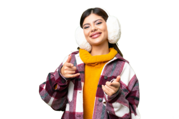 Young Russian woman wearing winter muffs over isolated chroma key background pointing to the front and smiling