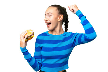 Young Arab woman holding a burger over isolated background celebrating a victory