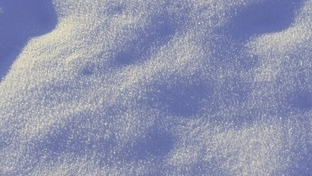 Snow surface. Fresh snow cover. Snowflakes and sparkles on sunny snow texture. Winter background. Small depth of field. Snowy surface with shiny ice crystals. Frozen details. Sunny frozen weather day.
