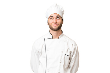 Young handsome chef man over isolated background and looking up