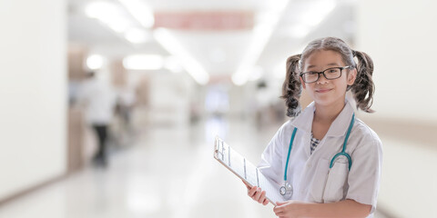 Kid's career inspiration and health care, medical insurance concept with girl child in white doctor or nurse lab gown with blurry background medical clinic healthcare service center or hospital