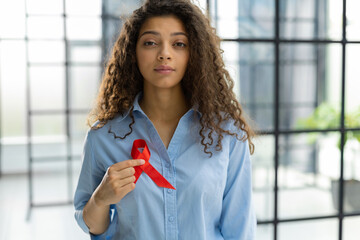 Woman holding red ribbon for december world aids day. Healthcare concept. - obrazy, fototapety, plakaty