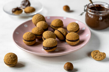 Hazelnut biscuits baci di dama or lady's kisses are traditional Italian dessert made as a sandwich with two cookies and chocolate cream. 
