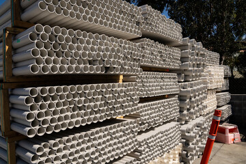 A stack of white PVC conduit pipes for plumbing and electrical construction work.