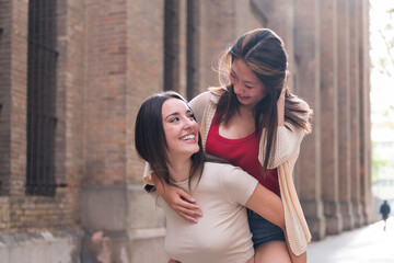 two young women on piggyback looking into each other's eyes smiling with love, concept of...