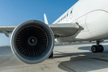 Unidentified plane engine and fuselage parked on airport runway with blue sky and copy space.