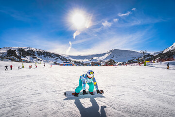 Woman, falling down when learning how to ride on a snowboard. Winter ski holidays in El Tarter,...