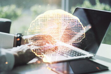 Double exposure of creative artificial Intelligence symbol with hands typing on laptop on background. Neural networks and machine learning concept