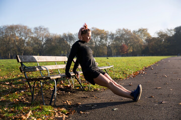 Full length of woman exercising by park bench