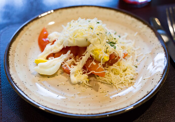 plate with a mix of tomatoes, cheese, eggs with french sauce
