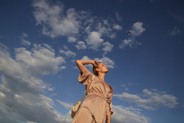 Beautiful young woman raising arms under blue sky, concept of freedom, hapiness and joy