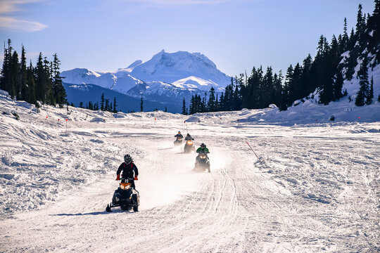 Group of men snowmobiling, Callaghan Valley, Whistler, British Columbia, Canada