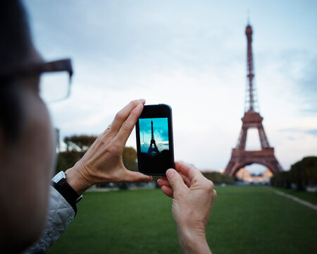 A woman taking a photo of the Eiffel Tower.