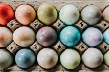 Overhead shot of close up of dyed Easter eggs in egg carton