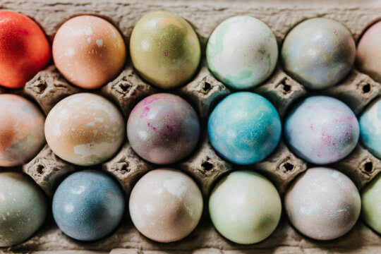 Overhead shot of close up of dyed Easter eggs in egg carton