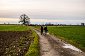 A woman walks along agricultural fields with her son