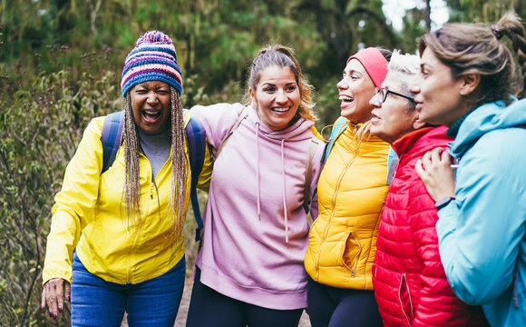 Multiracial women having fun during trekking day in mountain forest - Travel, nature and friendship concept - Focus on african female hat