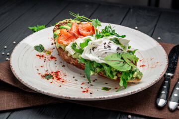 Bruschetta with sliced avocado, feta cheese, pesto sauce, poached egg and salted salmon.