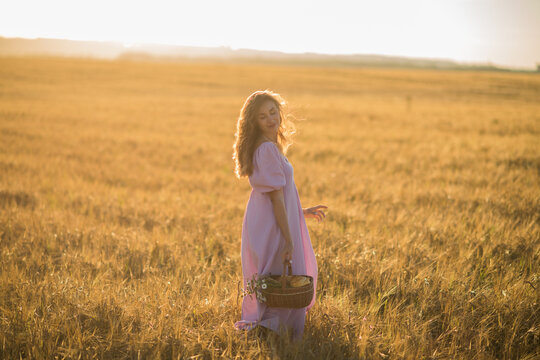 a happy girl with dark long hair walks in a wheat field at sunset, the concept of happiness and unity with nature