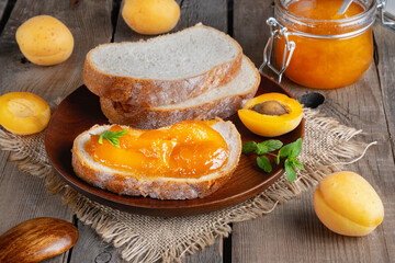 Toasts of bread with apricot jam and fresh fruits with mint on an old wooden table. Tasty breakfast