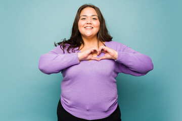 Adorable latin woman making a heart gesture