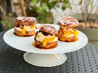 German cakes "Windbeutel".Baskets of custard dough, filling: whipped cream, candied almonds and tangerines, sprinkled with Powdered Sugar.