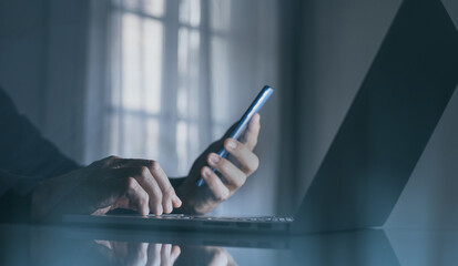 Businessman works on laptop with mobile phone. Technology, business, finance and marketing, concept.