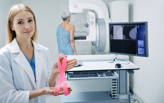 Breast cancer awareness ribbon in radiologist mammologist hands while mammogram procedure. Prevention of breast cancer