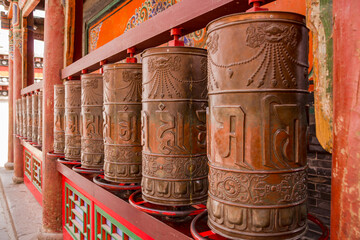 Vanishing point perspective of large prayer wheels or mani mills in a Tibetan monastery, Xining,...