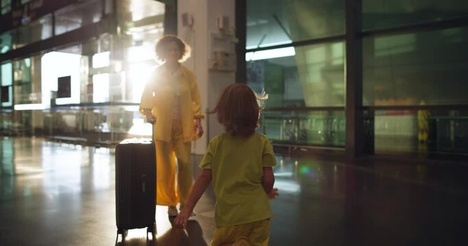 Cinematic scene, boy at railway station runs as fast as he can to woman, his mother, who has arrived from business trip. Woman has finally arrived from business trip to devote entire vacation to son.