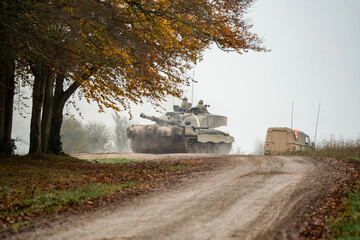 a large tank with soldiers by trees