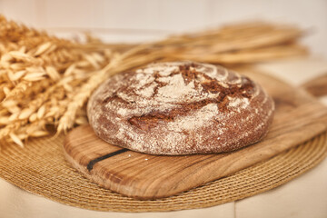 Freshly baked rye bread on a yeast-free starter and on a mixture of whole grain, rye and wheat flour. It lies on a napkin, next to a dried flower with grains. Selective focus. High quality photo