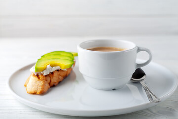 Coffee with cream and cream cheese sandwich with avocado