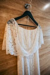 Beautiful white wedding dress hangs on a hanger indoors. Close-up photo, bride morning.