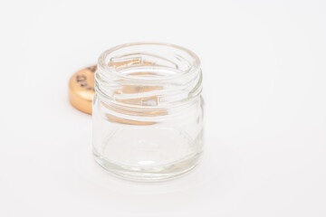 close up of a small empty clear glass jar with a bronze coloured screw down metal lid
