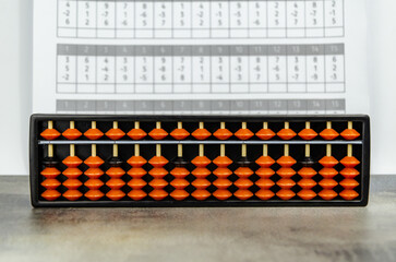 Abacus for mental arithmetic on background of sheet of paper with examples for calculation.