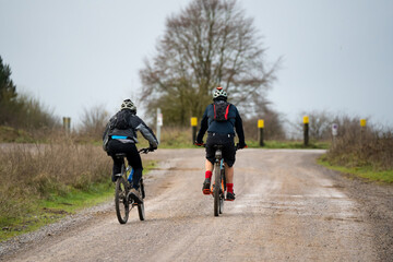 Fototapeta premium a pair of casual cyclists riding along across a country mud track