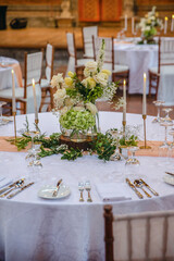 Beautiful table setting decorated with lighted candles, tableware, flowers, accessories for a party, wedding reception, gala banquet or other holiday event.