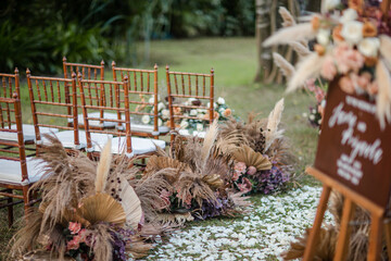 Wedding wooden chairs decorated with flowers. Rattan chairs standing by reception dinner table. Natural, rustic boho wedding decor - 561507630