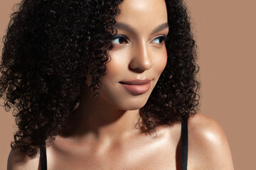 Beautiful young woman on beige background. Natural makeup, glowing dark skin