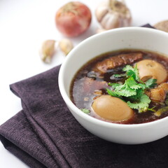 Egg and Pork in Sweet Brown Sauce served in a white cup. In restaurants in Thailand, stewed eggs are a popular dish in Thai people.