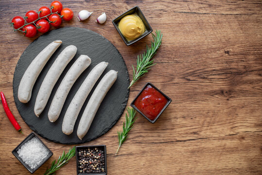 raw sausages with spices on a rustic background with copy space for your text