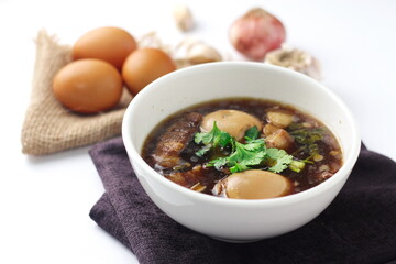Egg and Pork in Sweet Brown Sauce served in a white cup. In restaurants in Thailand, stewed eggs are a popular dish in Thai people.