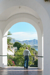 Fototapeta na wymiar An unidentified person stands at an arched lookout over the Mediterranean Sea on a sunny day in in Nerja, Spain. Image has copy space.