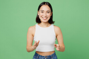 Young smiling fun happy cool woman of Asian ethnicity wears white tank shirt looking camera gesticulating hands talk isolated on plain pastel light green background studio. People lifestyle concept.